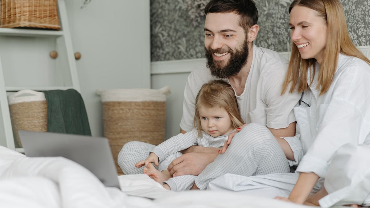 Family of three enjoying bonding time watching a laptop together at home.